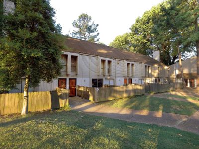 Row of townhouse units featuring individual fenced patio spaces and concrete walkways at Pinewood Manor apartments and townhomes in Memphis.