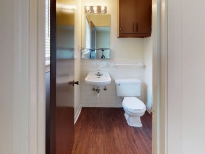 Full apartment bathroom with a white tiled shower and tub combination, dark wood vanity cabinets, and dark vinyl floors at Pinewood Manor apartments and townhomes in Memphis.