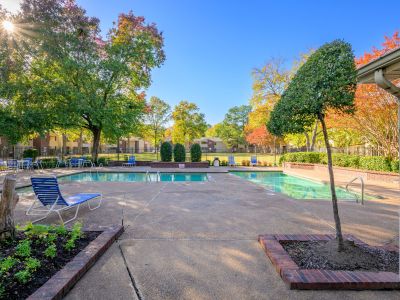 Sparkling resident swimming pool surrounded by lounge chairs and vibrant autumn trees at Rocky Creek Apartments in Southaven, Mississippi.