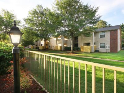 Landscaped apartment courtyard with a lit lamp post, metal fence, and green lawns at Rocky Creek Apartments in Southaven, Mississippi