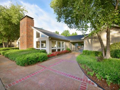 Leasing office entrance featuring large windows, a brick chimney, and landscaped walkways at Rocky Creek Apartments in Southaven, Mississippi
