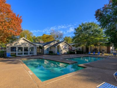 Outdoor community swimming pool with a concrete sun deck next to the leasing office building at Rocky Creek Apartments in Southaven, Mississippi.