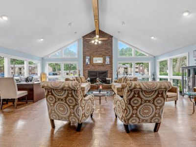 Spacious resident clubhouse lounge with vaulted ceilings, patterned armchairs, and a brick fireplace at Rocky Creek Apartments in Southaven, Mississippi.