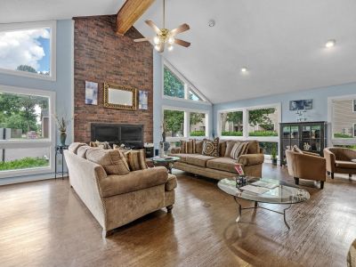 Clubhouse seating area showcasing large windows, a brick fireplace, and comfortable sofas at Rocky Creek Apartments in Southaven, Mississippi.