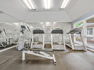 On-site fitness center featuring a row of treadmills and a weightlifting bench facing a mirror at Rocky Creek Apartments in Southaven, Mississippi.