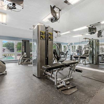 Bright exercise room equipped with stationary bikes, strength training machines, and wall mirrors at Rocky Creek Apartments in Southaven, Mississippi.