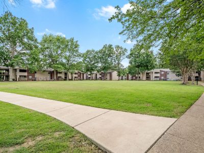 Expansive green courtyard lawn framed by a concrete walking path and residential buildings at Rocky Creek Apartments in Southaven, Mississippi