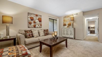 Cozy living room featuring neutral carpet, a comfortable sofa, and a sliding glass door at Rocky Creek Apartments in Southaven, Mississippi