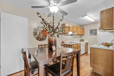 Wooden dining table set under a ceiling fan adjacent to a galley kitchen at Rocky Creek Apartments in Southaven, Mississippi.