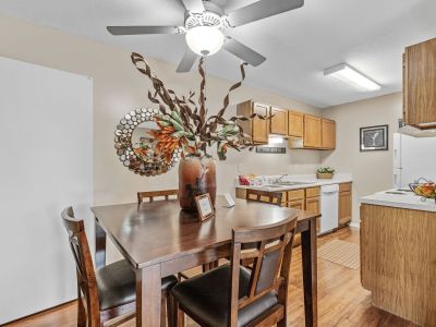 Wooden dining table set under a ceiling fan adjacent to a galley kitchen at Rocky Creek Apartments in Southaven, Mississippi.