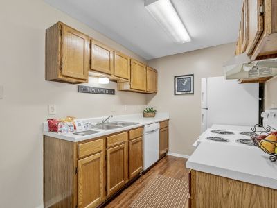 Galley kitchen equipped with traditional oak cabinets and white appliances at Rocky Creek Apartments in Southaven, Mississippi.