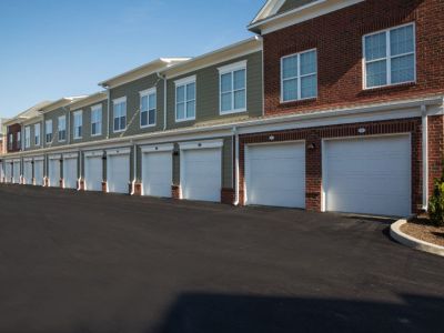 Long row of attached private garages beneath residential townhomes at The Signature at Schilling Farms apartments in Collierville.