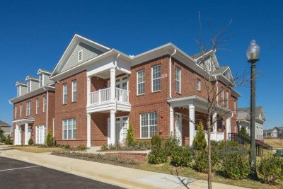 Modern two-story brick residential buildings featuring private balconies and white pillars at The Signature at Schilling Farms apartments in Collierville.