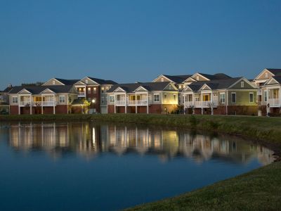 Scenic evening view of community apartments reflecting onto a peaceful neighborhood lake at The Signature at Schilling Farms apartments in Collierville