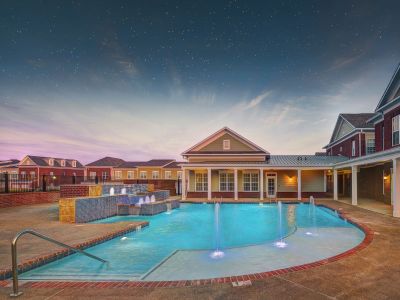 Luxury outdoor swimming pool area with illuminated fountains under a starry twilight sky at The Signature at Schilling Farms apartments in Collierville
