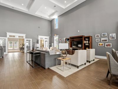 Grand resident clubhouse lounge with high ceilings, comfortable sofa seating groups, and wood-look flooring at The Signature at Schilling Farms apartments in Collierville.