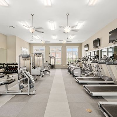On-site fitness center fully equipped with rows of modern treadmills, ellipticals, and strength training machines at The Signature at Schilling Farms apartments in Collierville