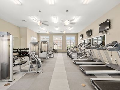 On-site fitness center fully equipped with rows of modern treadmills, ellipticals, and strength training machines at The Signature at Schilling Farms apartments in Collierville