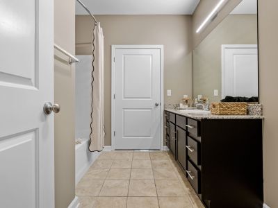 Modern bathroom featuring a dark vanity, granite countertops, and neutral tile floors at The Signature at Schilling Farms apartments in Collierville near Memphis.