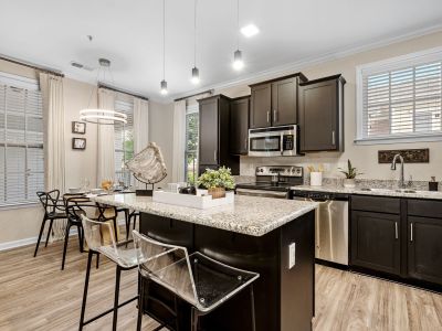 Modern kitchen with a granite island, clear barstools, and dark cabinets at The Signature at Schilling Farms apartments in Collierville near Memphis.