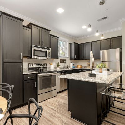Full kitchen view showcasing a granite island breakfast bar and stainless steel appliances at The Signature at Schilling Farms apartments in Collierville near Memphis.