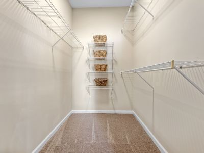 Spacious walk-in closet with carpeted floors and built-in wire shelving organizers at The Signature at Schilling Farms apartments in Collierville near Memphis.
