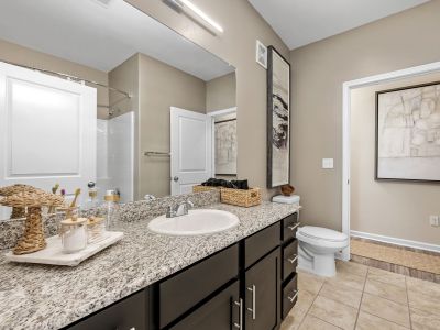 Modern bathroom showcasing a dark wood vanity with granite countertops and tile flooring at The Signature at Schilling Farms apartments in Collierville near Memphis