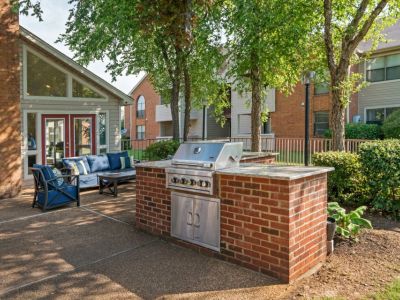 Outdoor community grilling area with brick accents, granite countertops, and patio seating at Southcrest Lake Apartments in Southaven