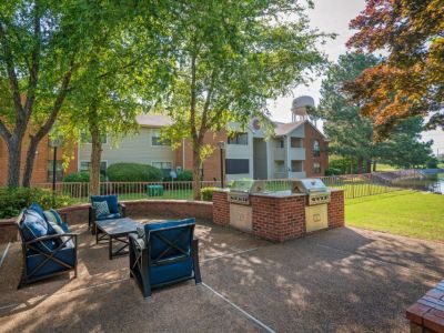Outdoor community patio with blue cushioned seating and a brick grilling station at Southcrest Lake Apartments in Southaven,