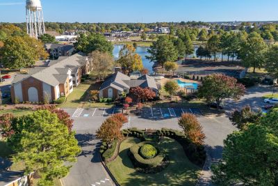 Aerial overview of the Southcrest Lake Apartments community grounds in Southaven, highlighting the residential buildings, outdoor pool, tennis courts, and central lake.