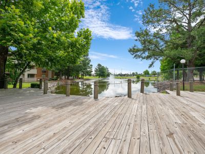 Spacious wooden sun deck overlooking a scenic neighborhood lake with a central water fountain at Southcrest Lake Apartments in Southaven,