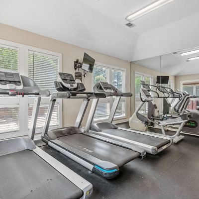 Bright fitness center featuring a row of modern treadmills facing large windows at Southcrest Lake Apartments in Southaven,