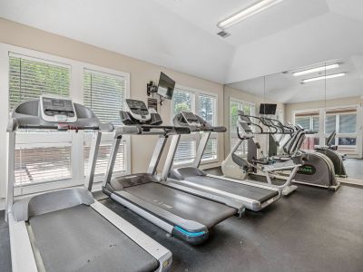 Bright fitness center featuring a row of modern treadmills facing large windows at Southcrest Lake Apartments in Southaven,