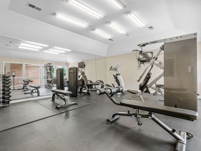 Community fitness center featuring weightlifting benches, a dumbbell rack, and strength training equipment at Southcrest Lake Apartments in Southaven,