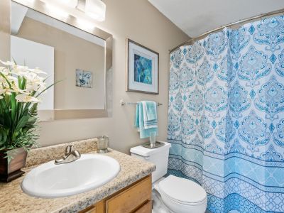 Bathroom with a neutral vanity countertop, large framed mirror, and a blue patterned shower curtain at Southcrest Lake Apartments in Southaven