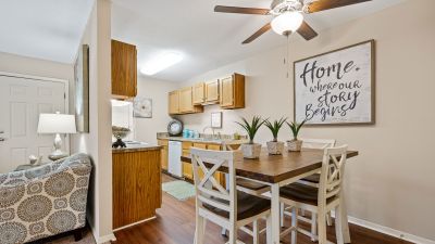 Wooden dining table and chairs on wood-style flooring adjacent to a kitchen at Southcrest Lake Apartments in Southaven