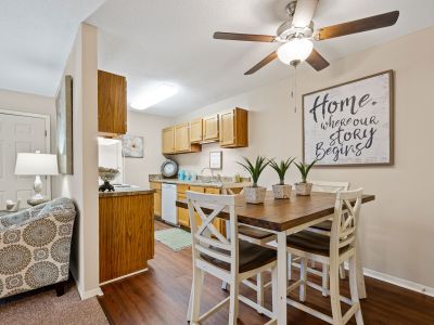 Wooden dining table and chairs on wood-style flooring adjacent to a kitchen at Southcrest Lake Apartments in Southaven