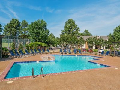 Sparkling outdoor swimming pool with blue lounge chairs on a spacious sun deck at Southcrest Lake Apartments in Southaven