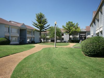 Paved courtyard walkway winding between residential buildings and green lawns at Edison Park apartments in downtown Memphis.