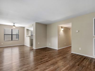 Spacious empty living room showing wood-style flooring, neutral paint, and an overhead ceiling fan at The Ellington at Kirby apartments in Memphis