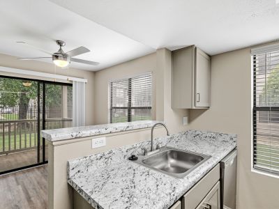 Kitchen with speckled granite-look countertops looking out toward a patio at The Ellington at Kirby apartments in Memphis.