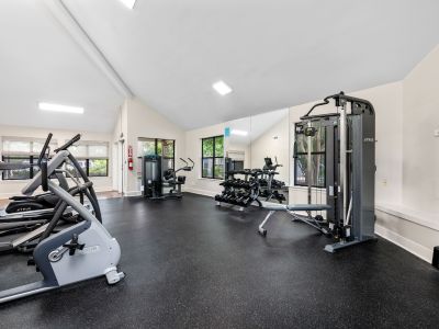 Fully equipped fitness space with cardio machines, a weight bench, and large wall mirrors at The Ellington at Kirby apartments in Memphis.