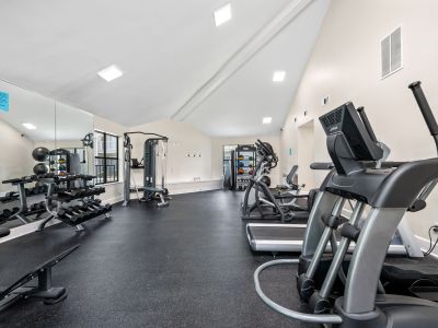 Bright fitness center layout featuring treadmills, a gym mirror, and black rubber flooring at The Ellington at Kirby apartments in Memphis.