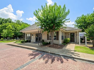 Exterior view of the community leasing office building with a paved brick walkway at The Ellington at Kirby apartments in Memphis.