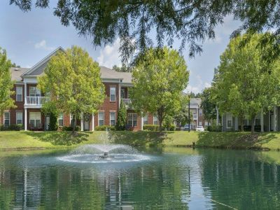 Scenic community pond featuring a running water fountain surrounded by manicured lawns and trees at The Westbury apartments near Germantown.
