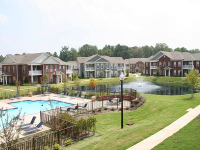 Elevated view of the pristine resort-style swimming pool and sun deck with lounge chairs adjacent to the central pond at The Westbury apartments near Germantown.