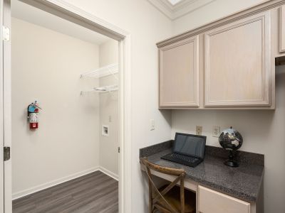 Built-in computer desk nook featuring granite countertops and upper cabinetry next to a laundry closet opening at The Westbury apartments near Germantown.