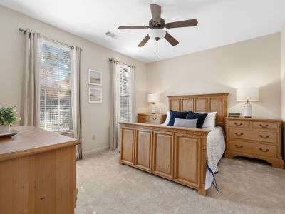 Spacious, well-lit apartment bedroom featuring a classic wooden matching furniture set and beige carpeting at The Westbury apartments near Germantown.
