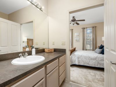 Modern bathroom vanity area with a dark countertop and ample cabinet storage looking through to the bedroom at The Westbury apartments near Germantown.