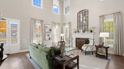 Upscale leasing office clubhouse clubroom featuring a high ceiling, white fireplace, green velvet sofa, and large windows at The Westbury apartments near Germantown.